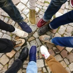 la unión hace la fuerza. Circle of sneakers on cobblestone pavement representing diversity and urban fashion.